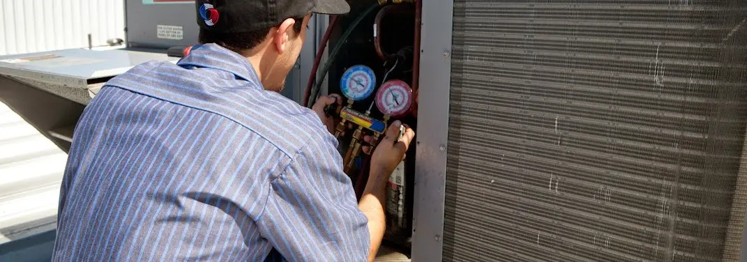 HVAC technician servicing a condenser unit in Horace