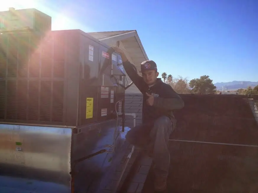 HVAC technician performing AC Tune-Up on a rooftop unit in Horace